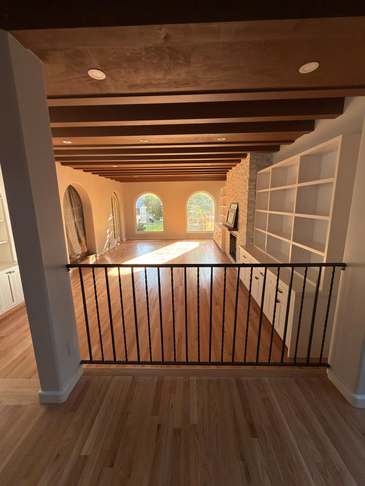 A completed ORCCI living room renovation with hardwood floors, ceiling beams, and built-in shelving